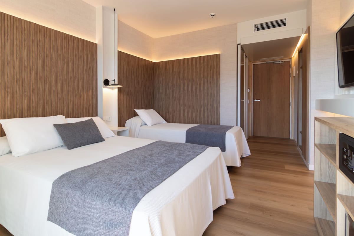 Habitación de hotel con dos camas, un televisor y una pared de madera.