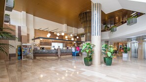 A spacious lobby with a reception desk, multiple potted plants, and a modern staircase. - Golden Port Salou & Spa (Salou)