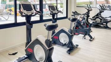 Un gimnasio con bicicletas estáticas, cinta de correr y máquina de remo.