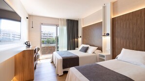 A hotel room with two beds, a desk, and a view of the city. - Golden Port Salou & Spa (Salou)