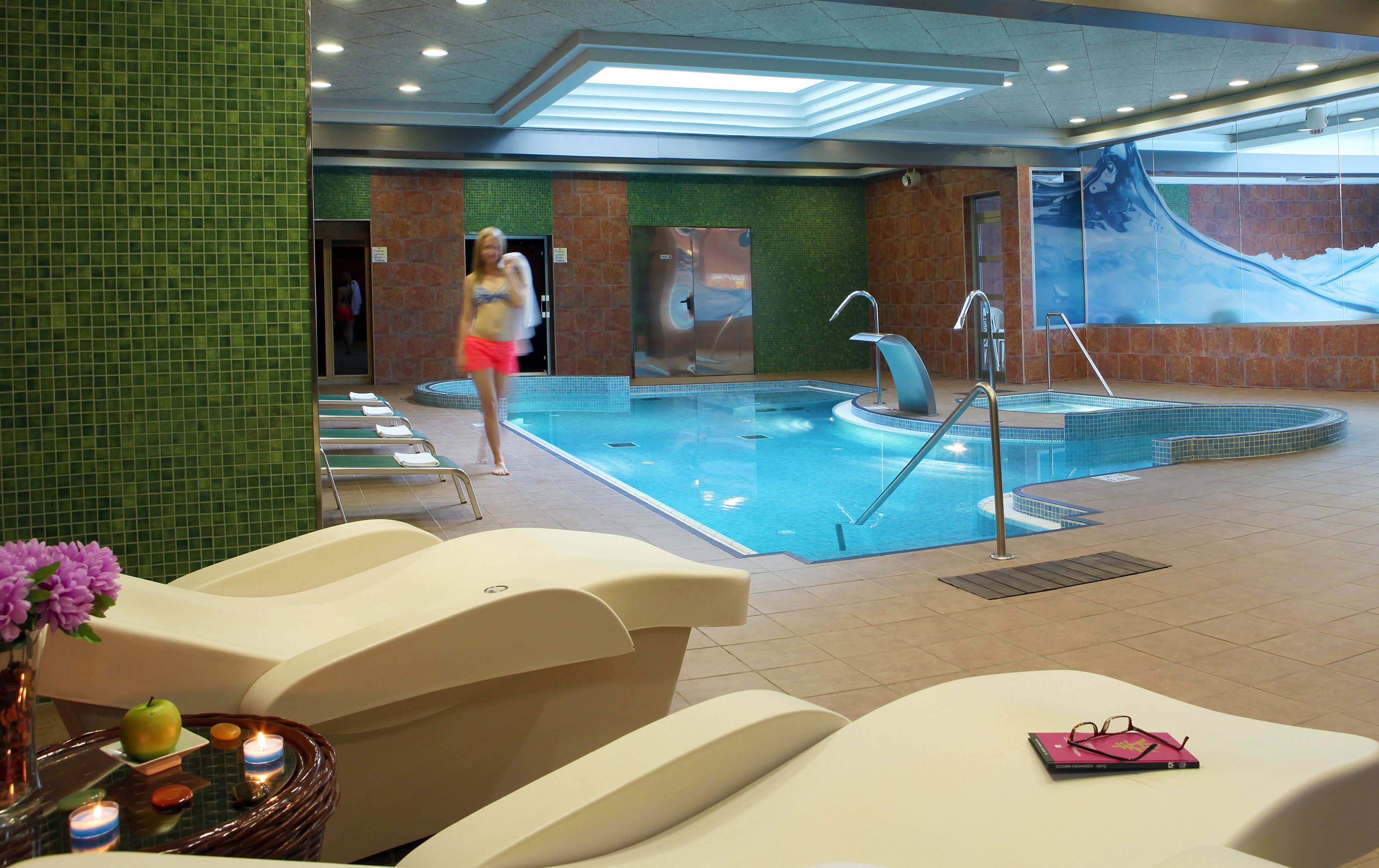Zwembadgedeelte van een hotel met ligbedden, een bubbelbad en een muurschildering.