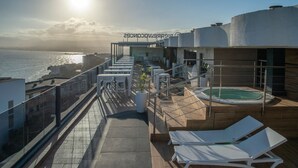 Una terraza en la azotea con piscina, tumbonas y vistas al mar.
