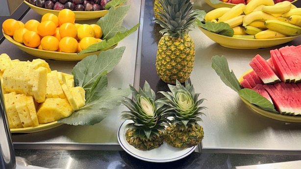 Een buffet met diverse soorten fruit en een centrale presentatie van ananassen.