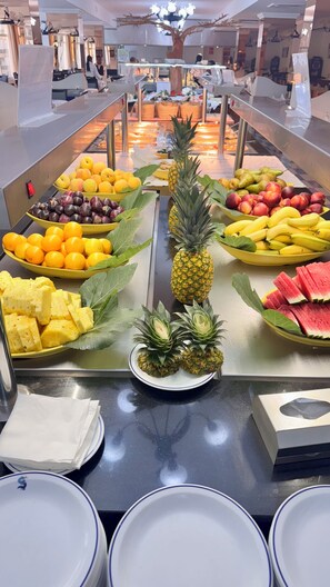 Un bufé con diversas frutas y una presentación central de piñas.