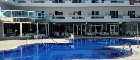 Un hotel de varios niveles con piscina, zona de estar al aire libre y balcones.