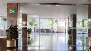 Een moderne lobby met marmeren zuilen, glazen deuren en potplanten.