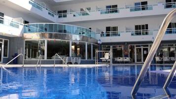 Alberca al aire libre, sombrillas en la alberca y camastros