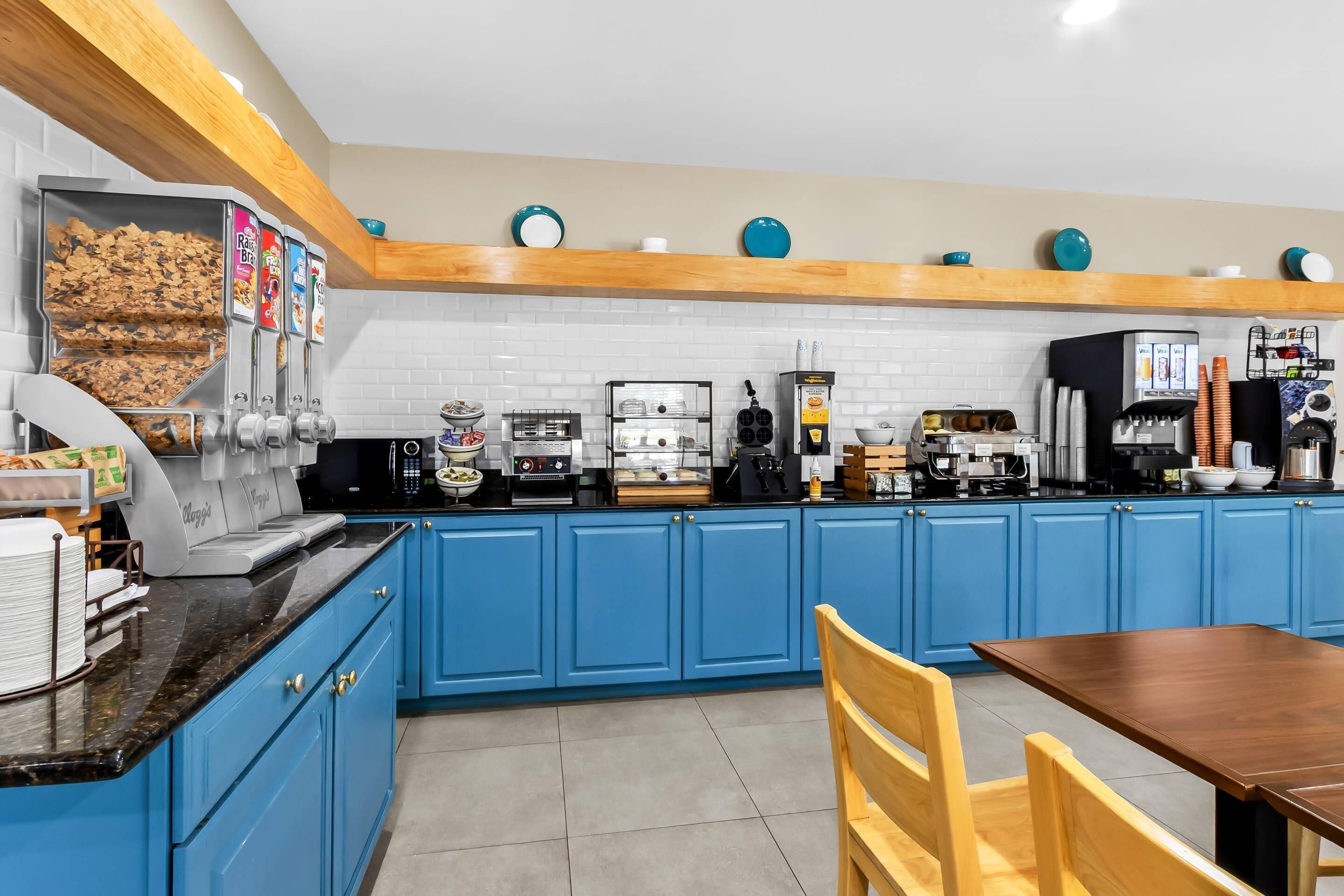 Una cocina con armarios azules, una máquina de café y una vitrina de alimentos.