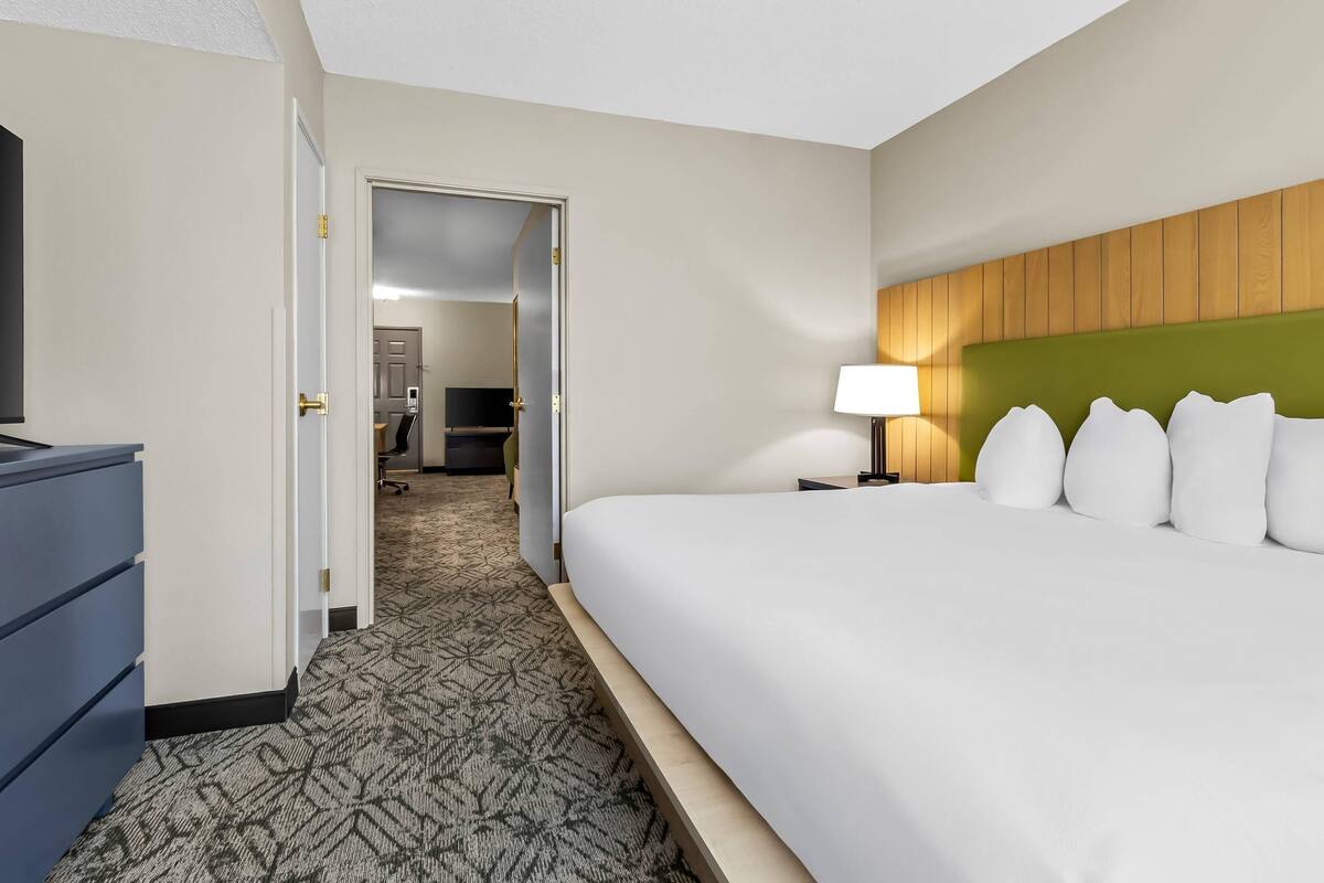 A hotel room with a bed, a desk, a lamp, and a wardrobe.