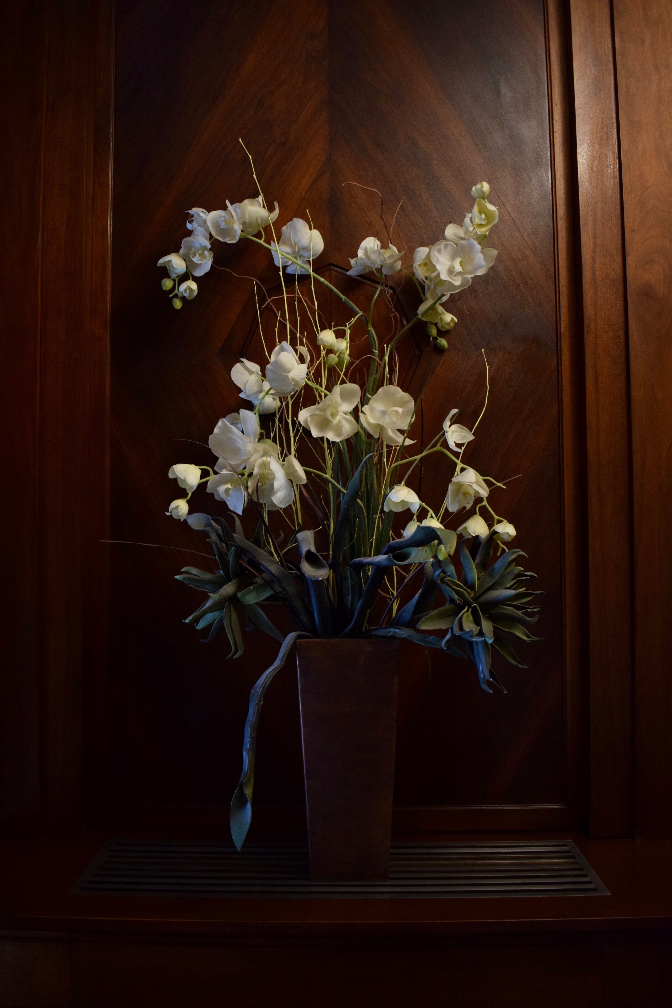 Un ramo de orquídeas blancas en un jarrón sobre una superficie de madera.