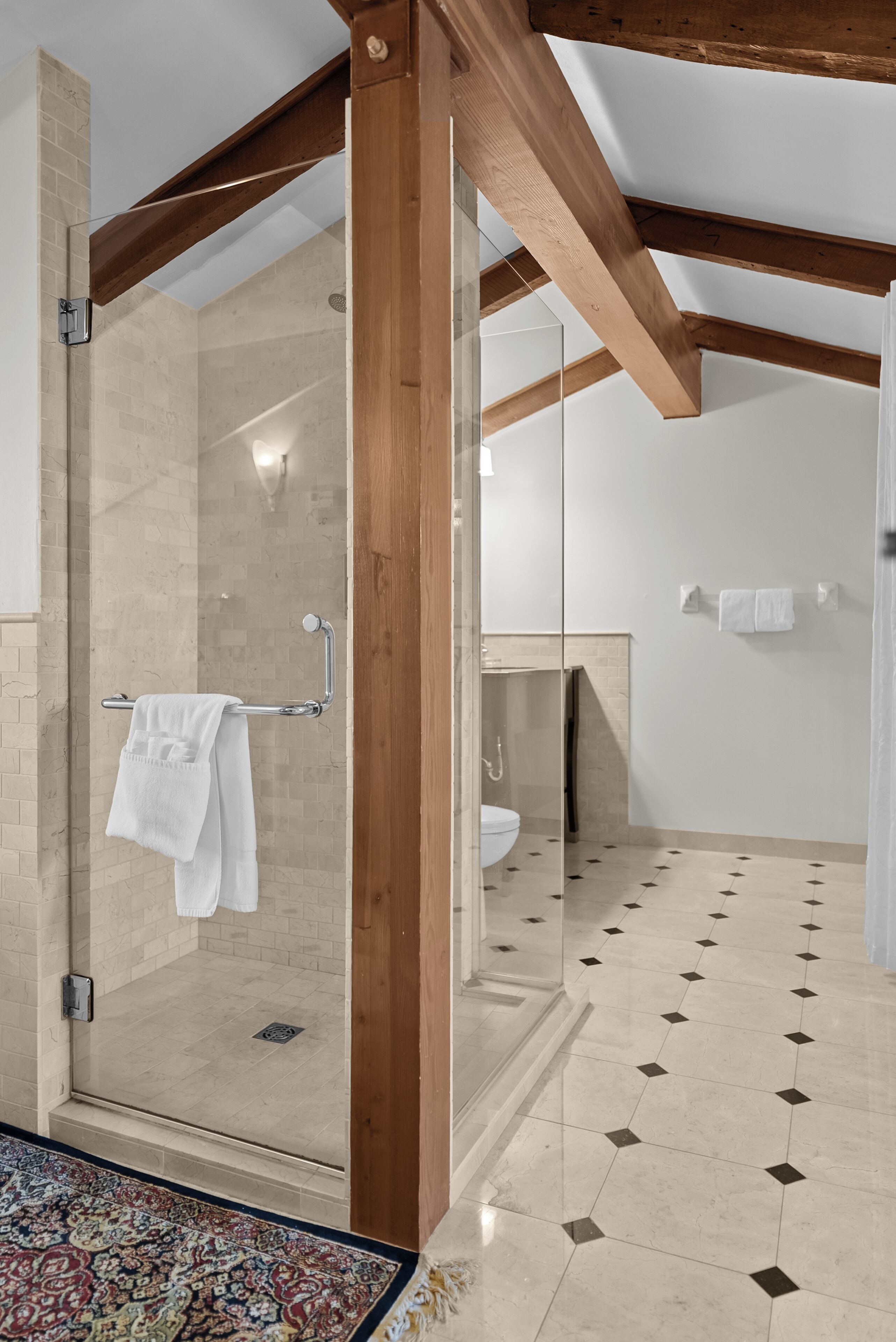 Un baño moderno con ducha de vidrio, techo de madera y piso estampado.
