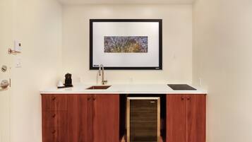 A modern kitchen with a built-in dishwasher, wooden cabinets, a white countertop, and a framed picture above the sink.