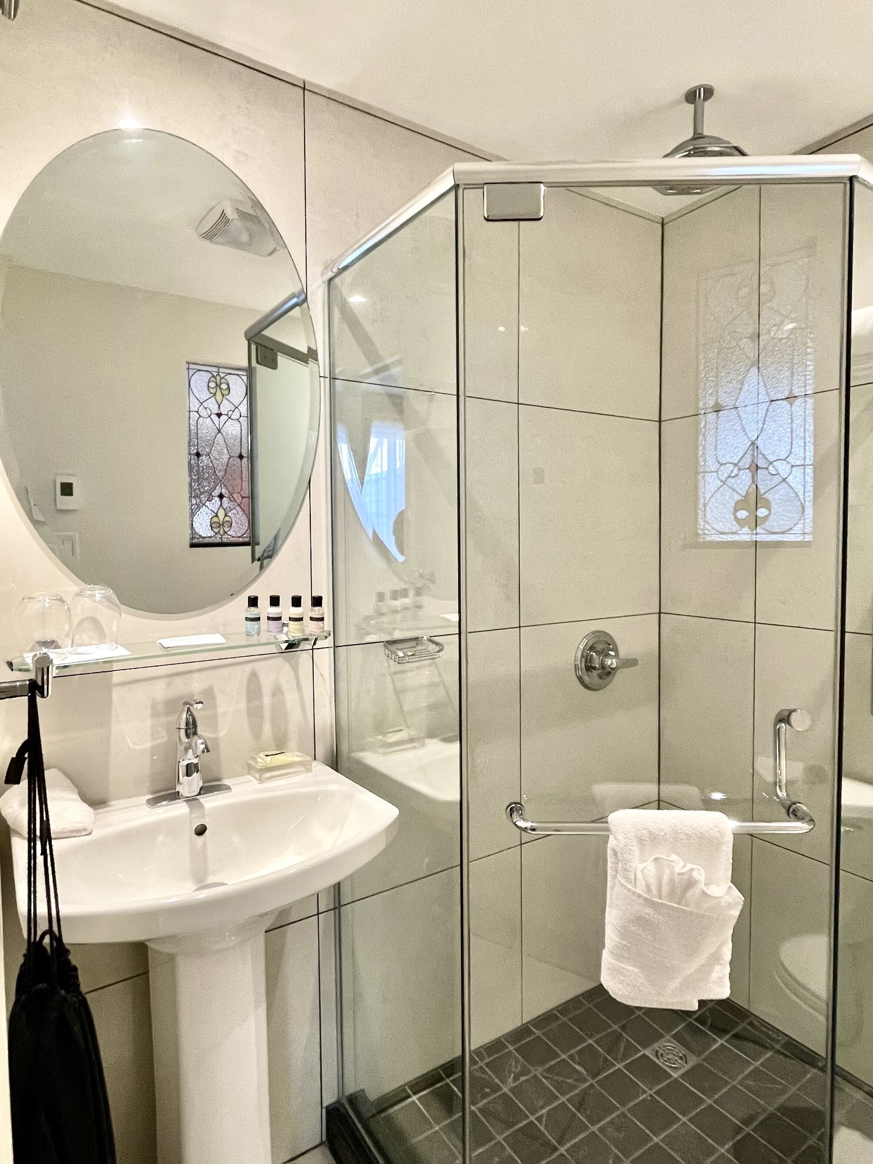 Een moderne badkamer met een douchecabine van glas, een witte wastafel en een grote spiegel.