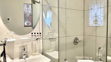 Een moderne badkamer met een douchecabine van glas, een witte wastafel en een grote spiegel.