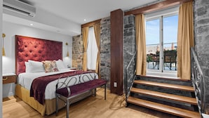 A bedroom with a large bed, a wooden staircase, and a view of the outside. - Le Manoir d'Auteuil - Par Aneyro (Québec City)
