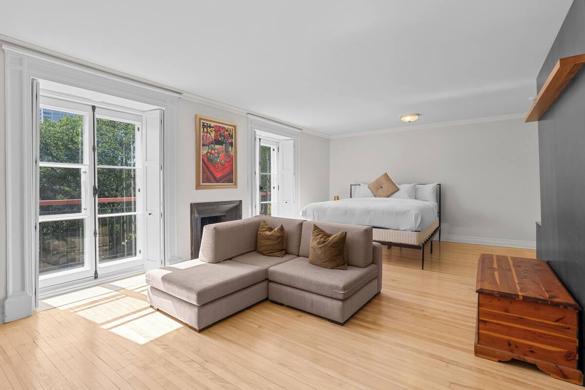 A modern bedroom with a sectional sofa, a bed, and a wooden bench.