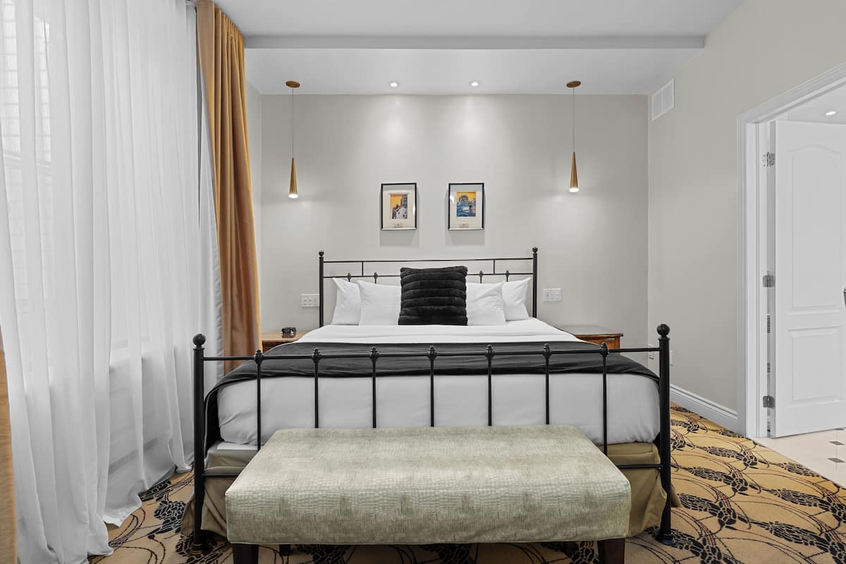 A bedroom with a bed, bedside tables, a bench, and two wall-mounted lights.