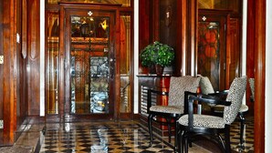 A lobby with a checkered floor, wooden doors, and leopard print chairs. - Le Manoir d'Auteuil - Par Aneyro (Québec City)