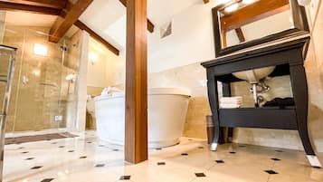 A modern bathroom with a glass shower enclosure, a white toilet, a large white bathtub, and a black vanity with a mirror.