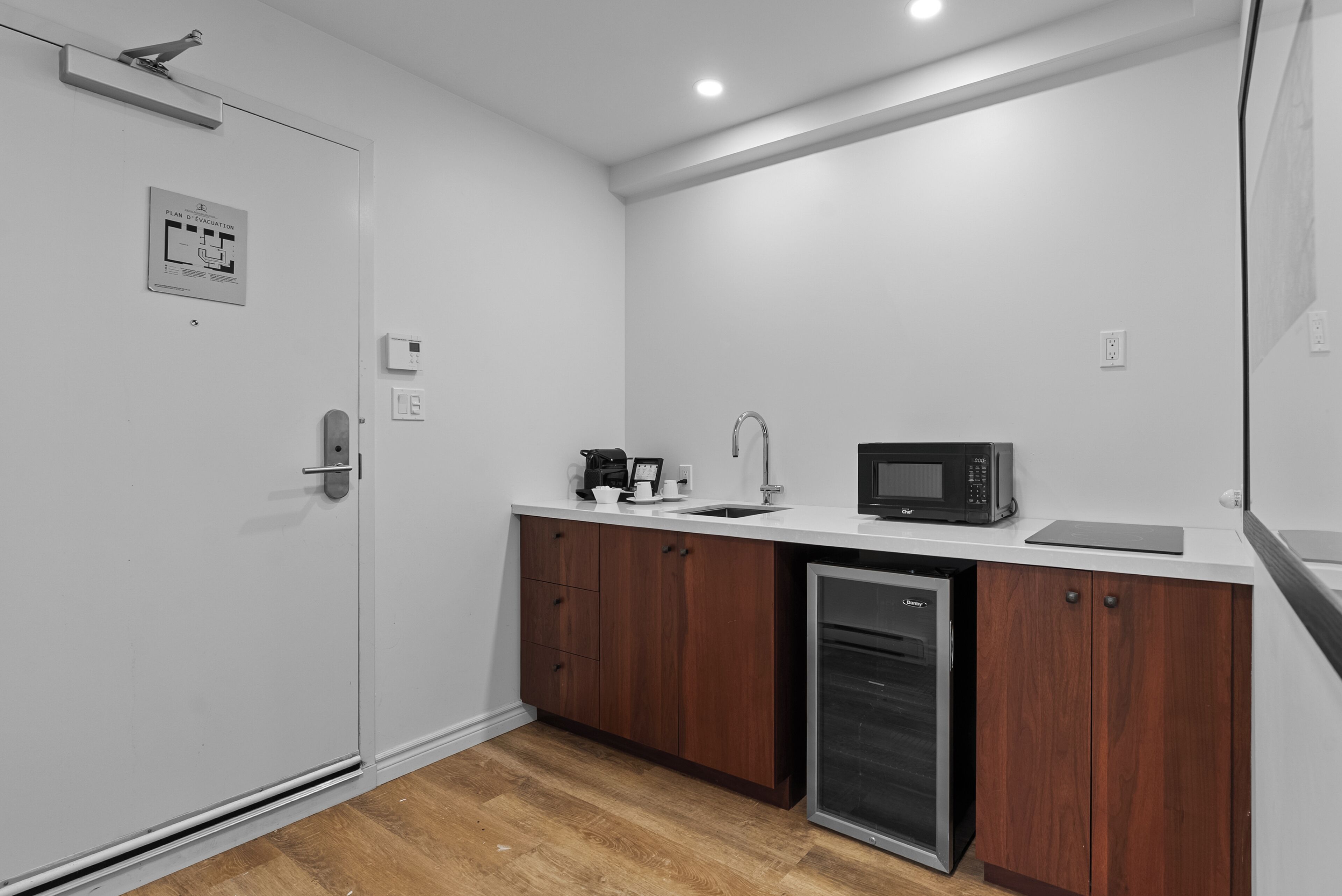 A compact kitchen with a dishwasher, a coffee maker, and a microwave.