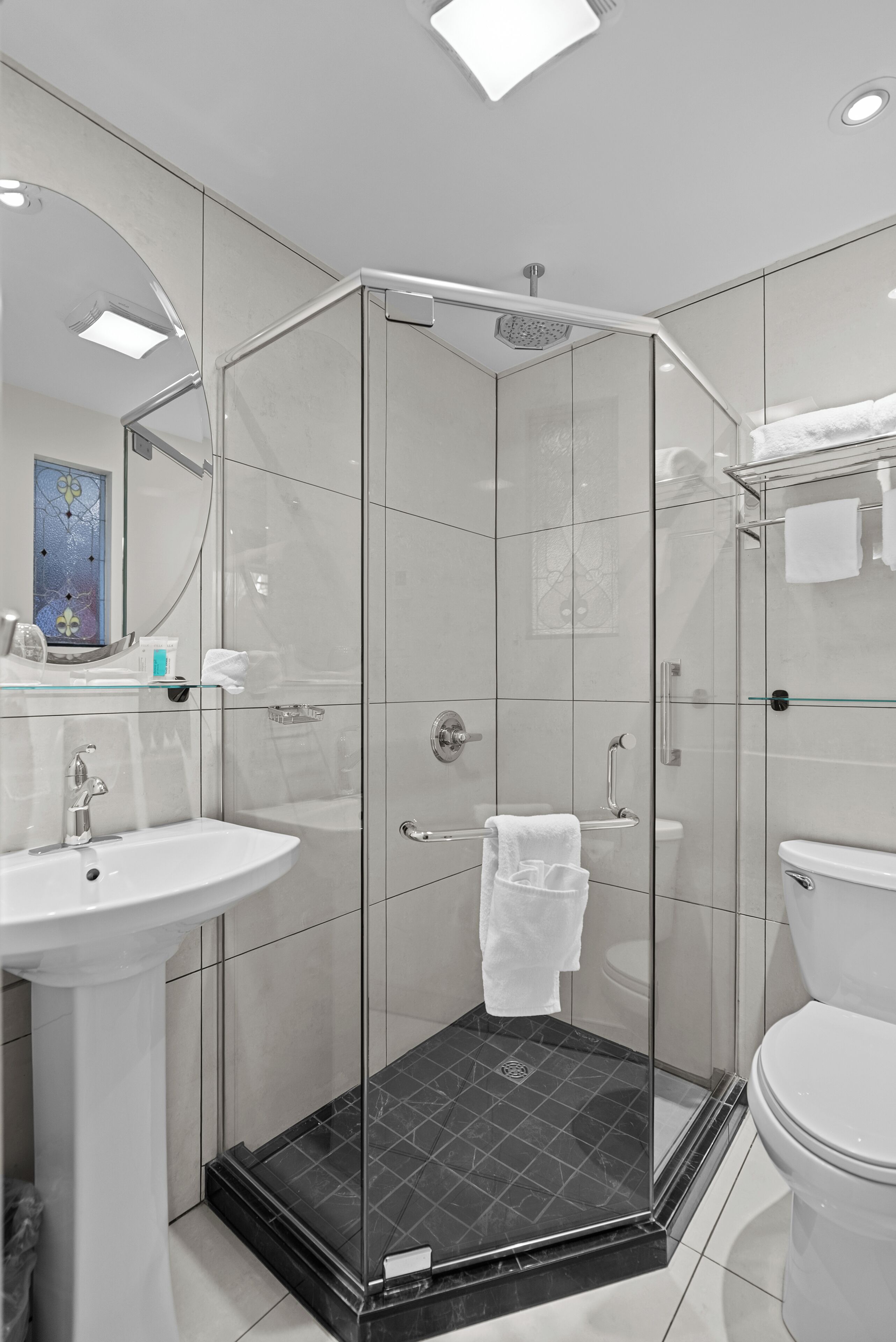 Een moderne badkamer met een douchecabine van glas, een wit wastafelmeubel en een toilet.