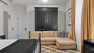 A hotel room with a bed, a sofa, a wardrobe, and a patterned carpet.