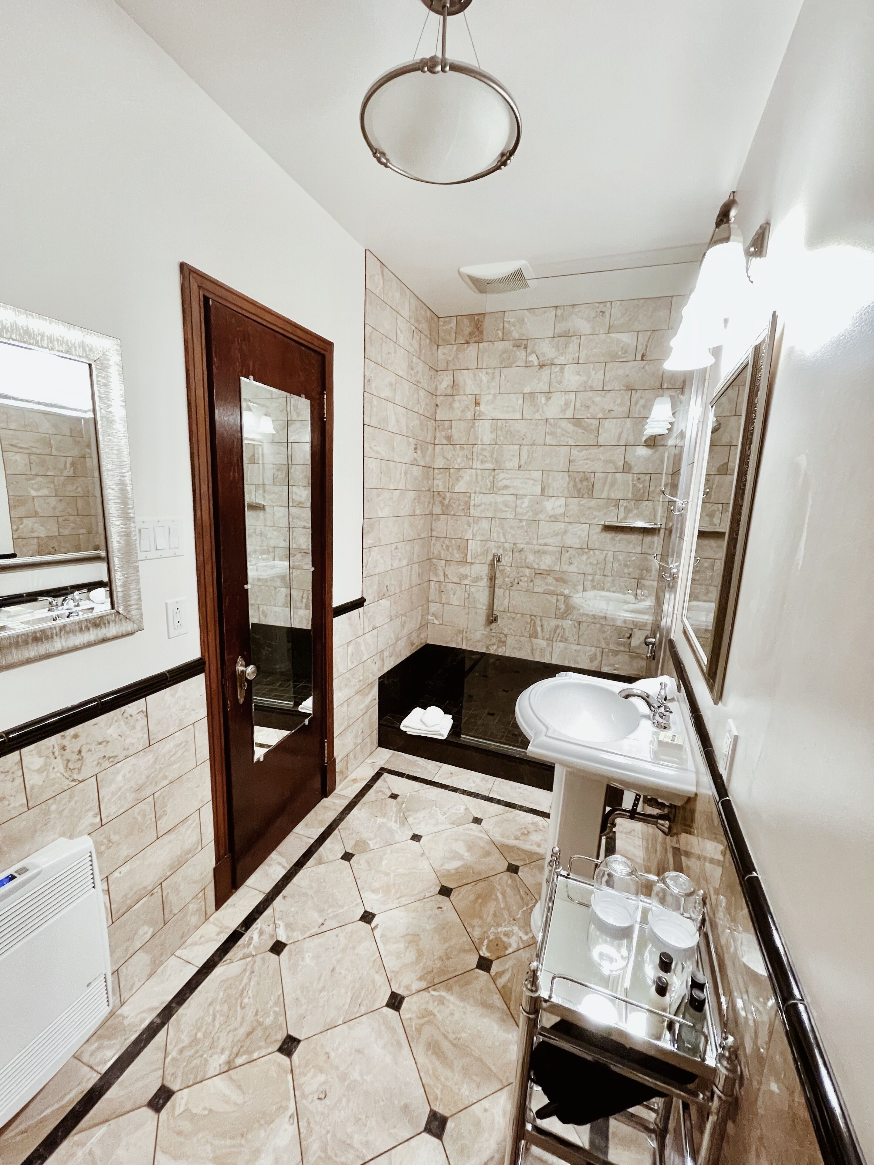 Un baño moderno con un espejo grande, un lavabo y una zona de ducha.