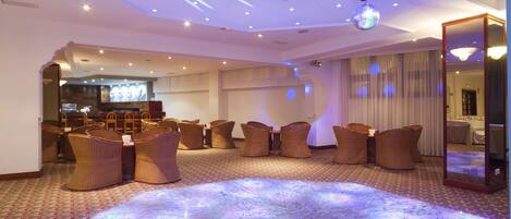 A spacious room with a marble floor, wicker chairs, and a disco ball on the ceiling.