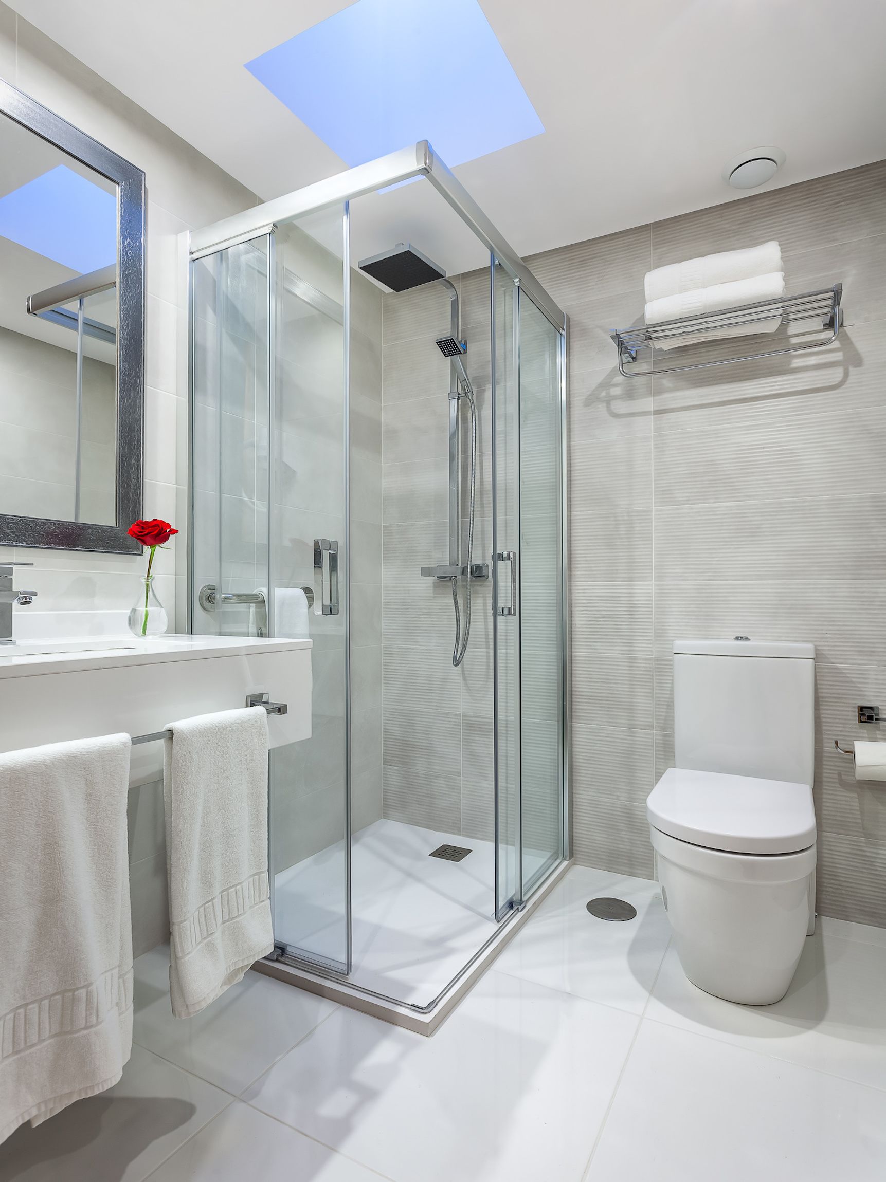 Un bany modern amb dutxa envidriada, un lavabo blanc, un vàter i una pervesura.
