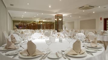A banquet hall with round tables set for a formal event, complete with white tablecloths, folded napkins, and cutlery.