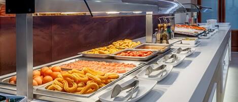 A buffet with various food items like fruits, pastries, and vegetables.