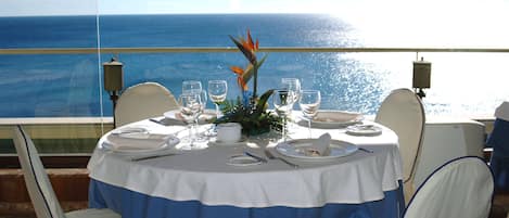 A table set for dining with a view of the ocean.