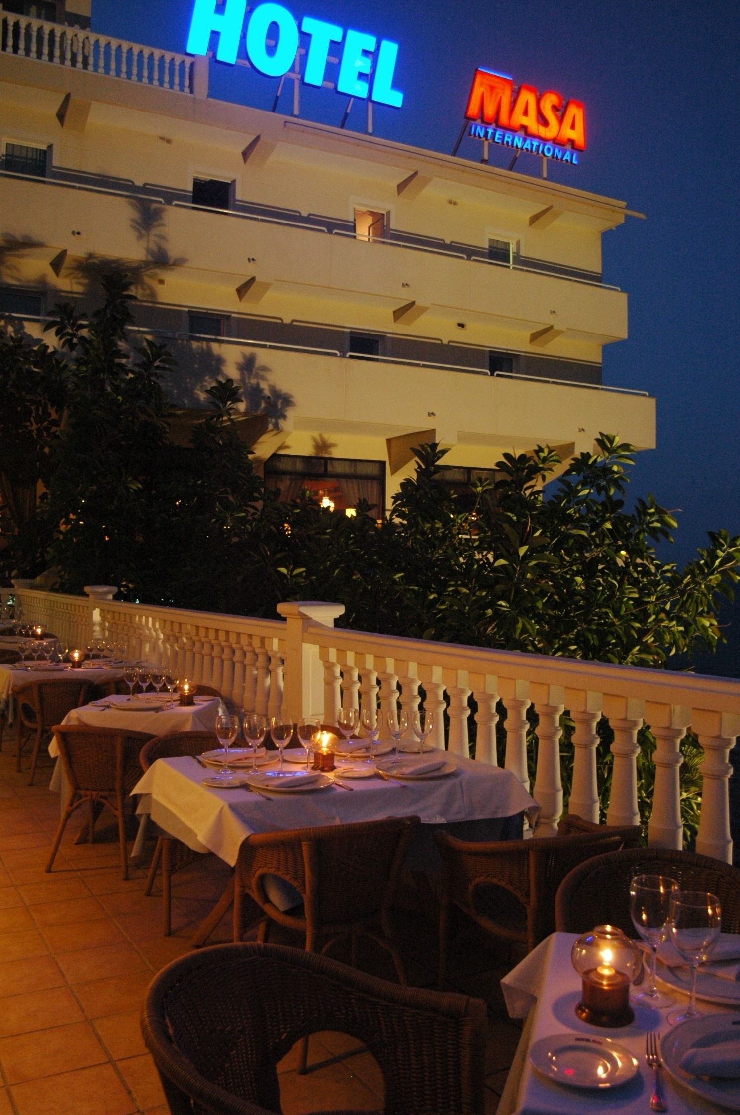 Un hotel con mesas de comedor al aire libre preparadas para los huéspedes.