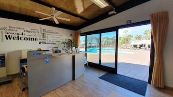 A reception desk with a view of an outdoor pool area.