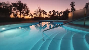 Una piscina al aire libre, sombrillas, sillones reclinables de piscina