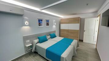 A modern bedroom with a large bed, a wooden headboard, and a television on the wall.