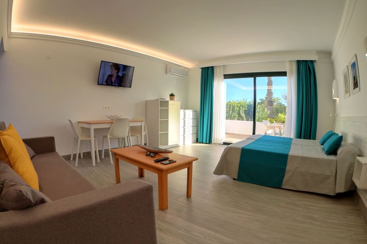 Ein Hotelzimmer mit einer Couch, einem Bett, einem Schreibtisch und einem Fernseher.