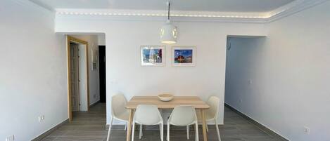Een eethoek met een tafel en stoelen, een hanglamp en twee ingelijste foto’s aan de muur.