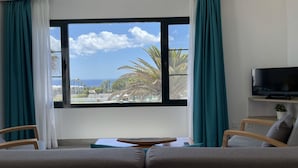A room with a large window, a television on a stand, and two chairs. - Palmeras Garden (Yaiza)