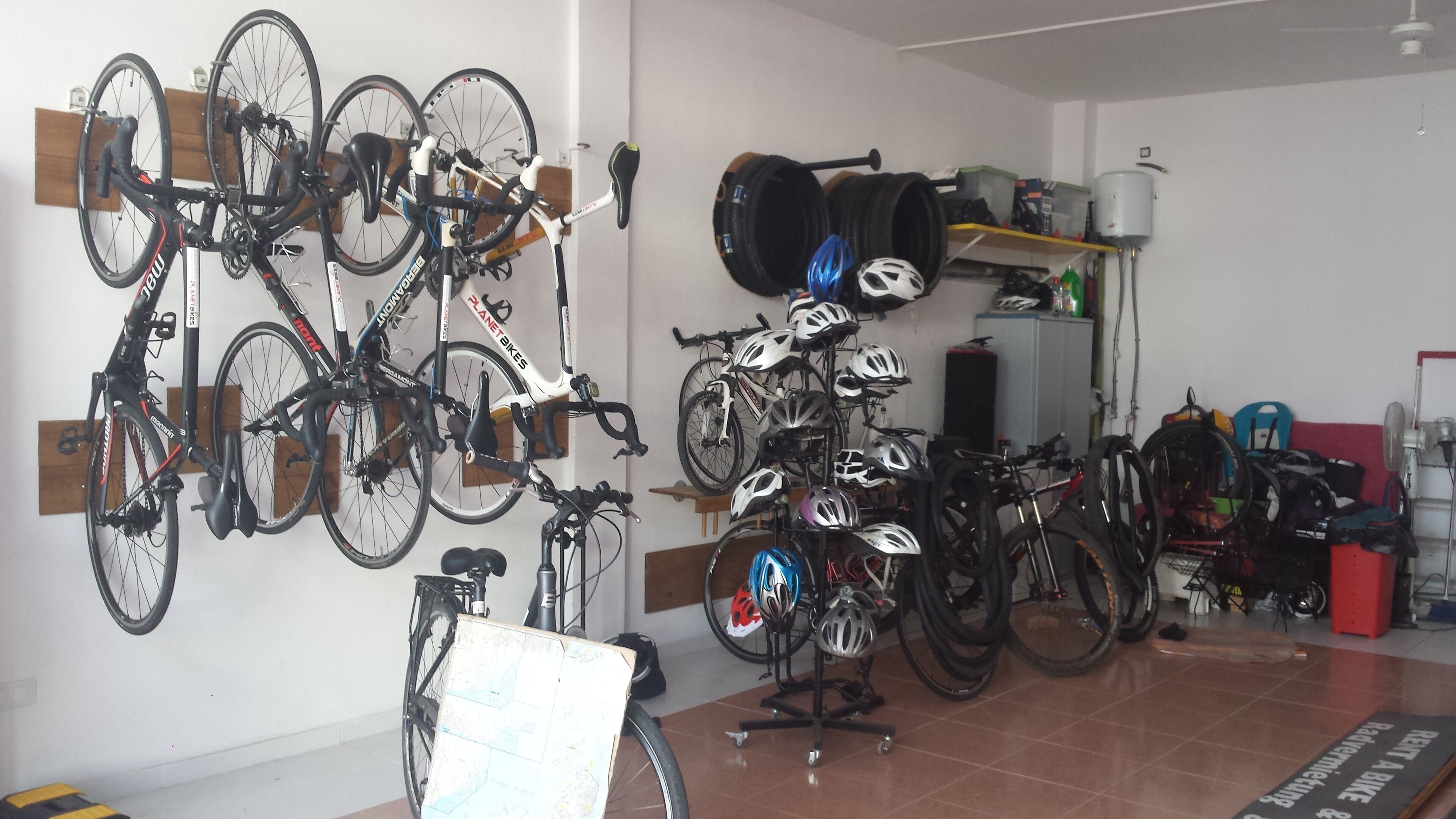Um espaço para guardar bicicletas, com várias bicicletas e capacetes.