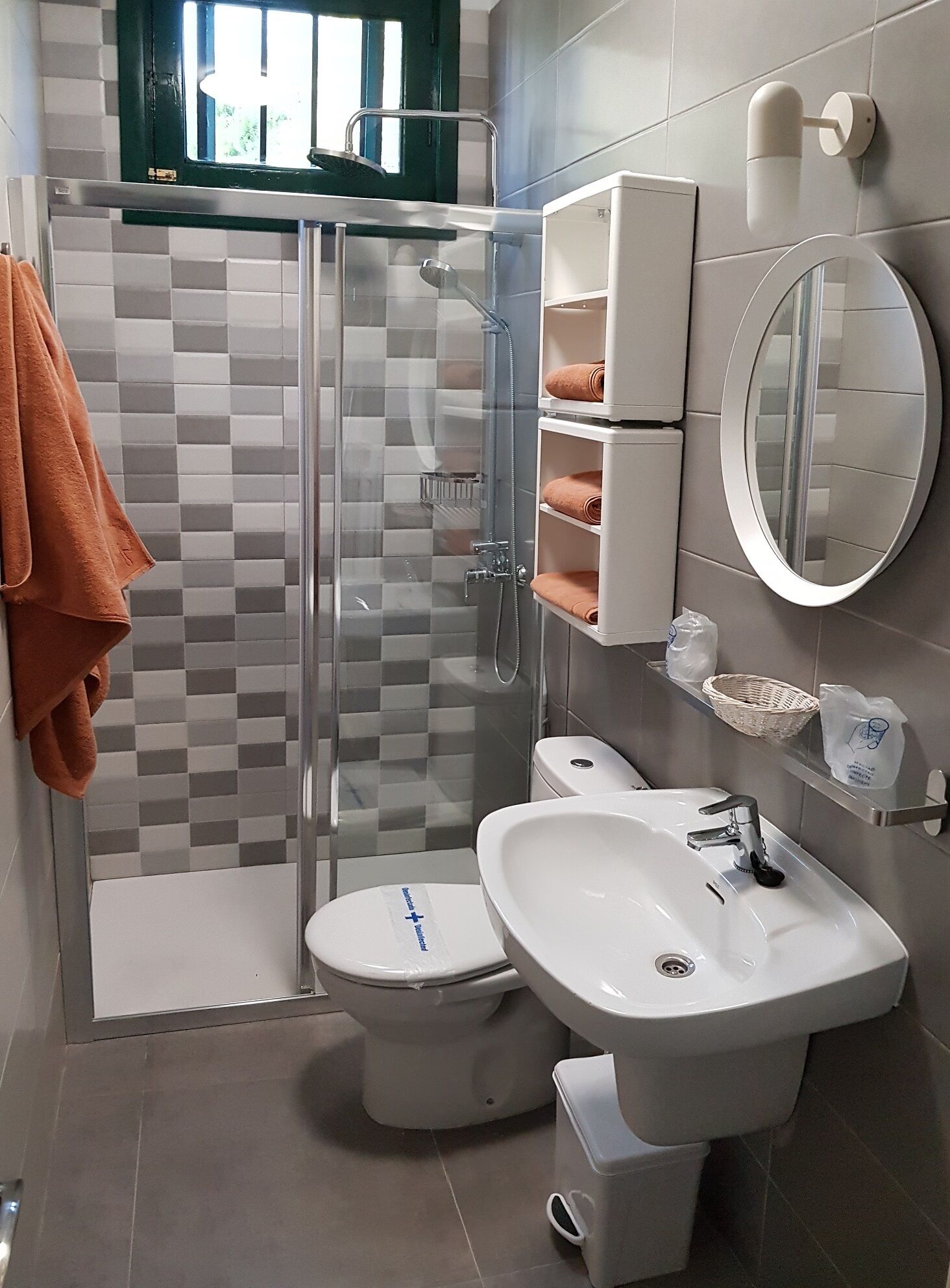 Ein modernes Badezimmer mit einer Glasdusche, einem weißen Waschbecken und einer Toilette.