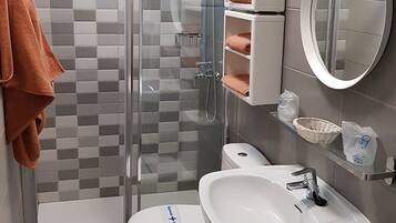 Une salle de bain moderne avec une douche à parois de verre, un lavabo blanc et des toilettes.