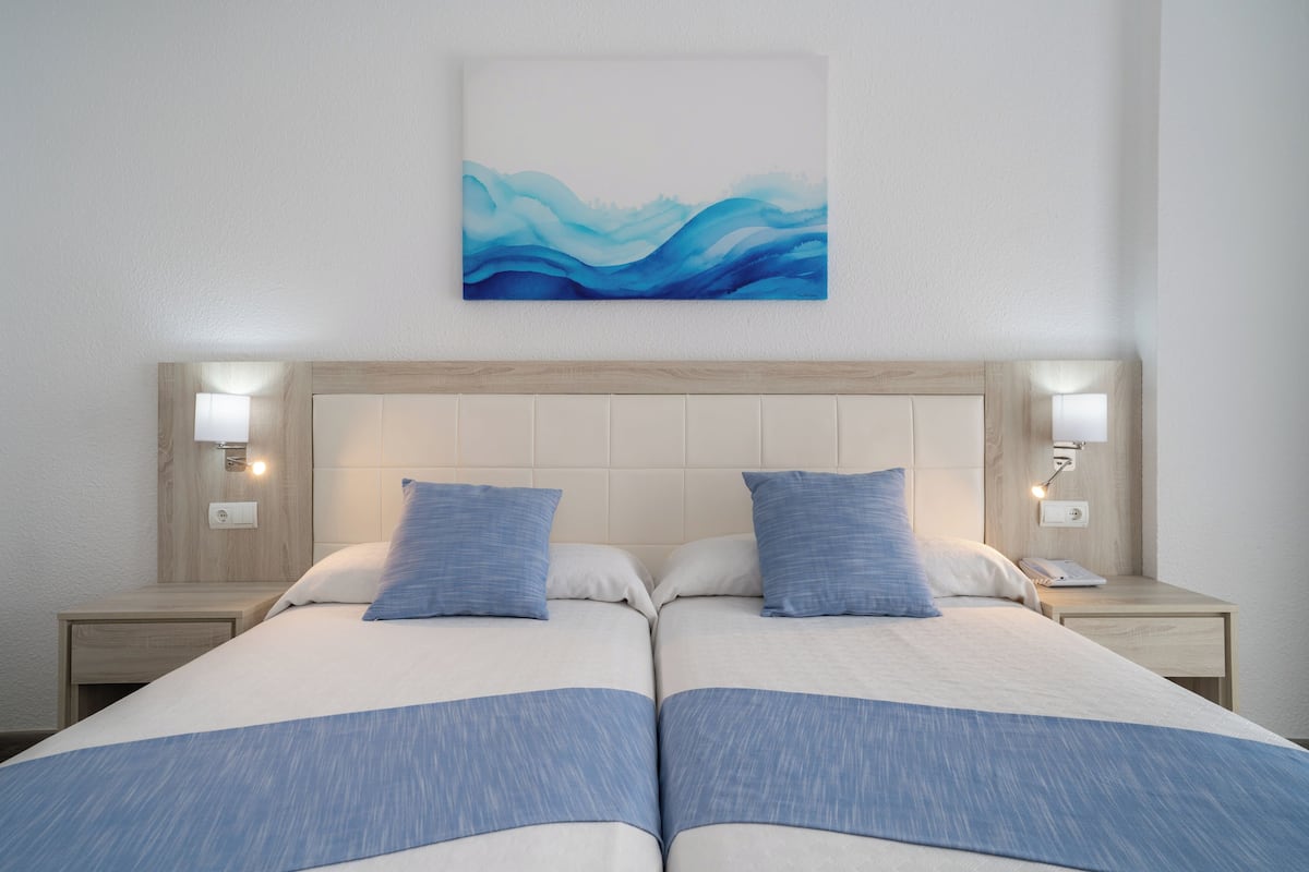A double bed with a headboard, two bedside tables, and a wall-mounted artwork.