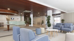 A modern lobby with blue and grey seating, a reception desk, and decorative plants. - Hotel Palia Las Palomas (Torremolinos)