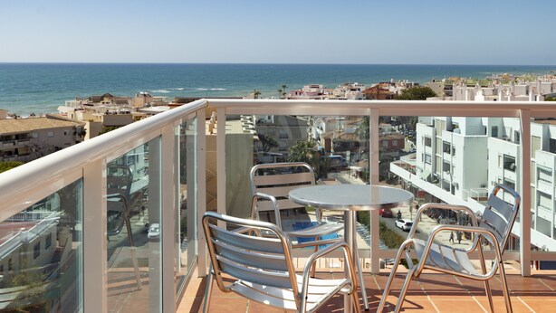 A balcony with a glass railing overlooking a coastal cityscape. - Hotel Palia Las Palomas (Torremolinos)
