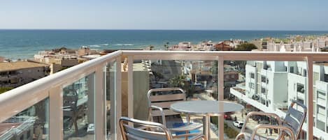 Un balcon doté d’une balustrade en verre, offrant une vue sur le paysage urbain de la côte.