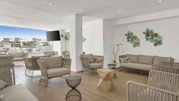 Een moderne woonkamer met een bank, stoelen, een salontafel en decoratieve wandkunst.