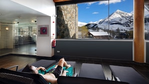 A person relaxing on a massage table in a room with a large window overlooking a snowy mountain. - Aparthotel Hg Cerler (Benasque)