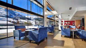A modern hotel lobby with large windows offering a view of snow-covered mountains. - Aparthotel Hg Cerler (Benasque)