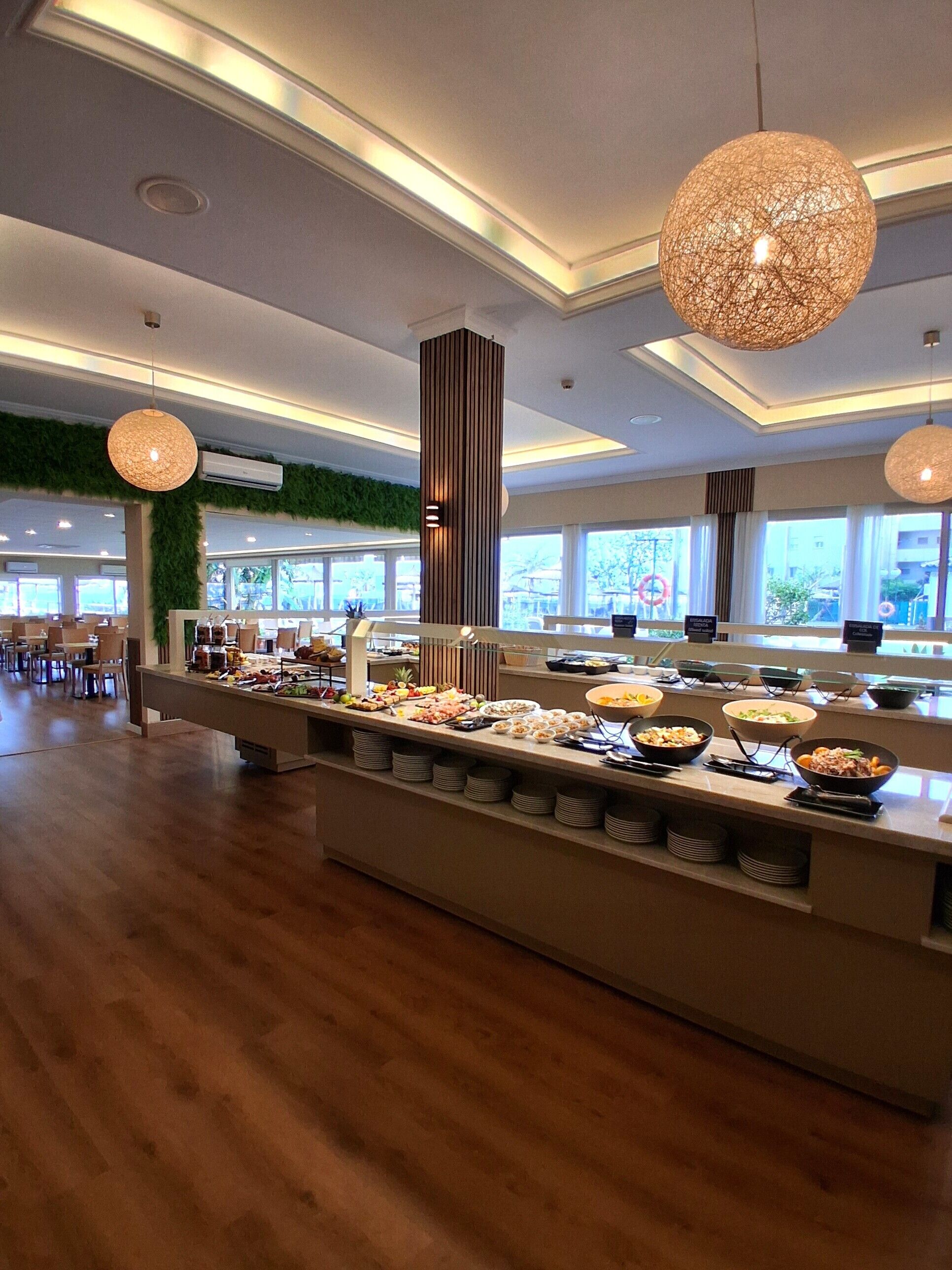 A buffet area with a variety of food options, a central column, and hanging pendant lights.